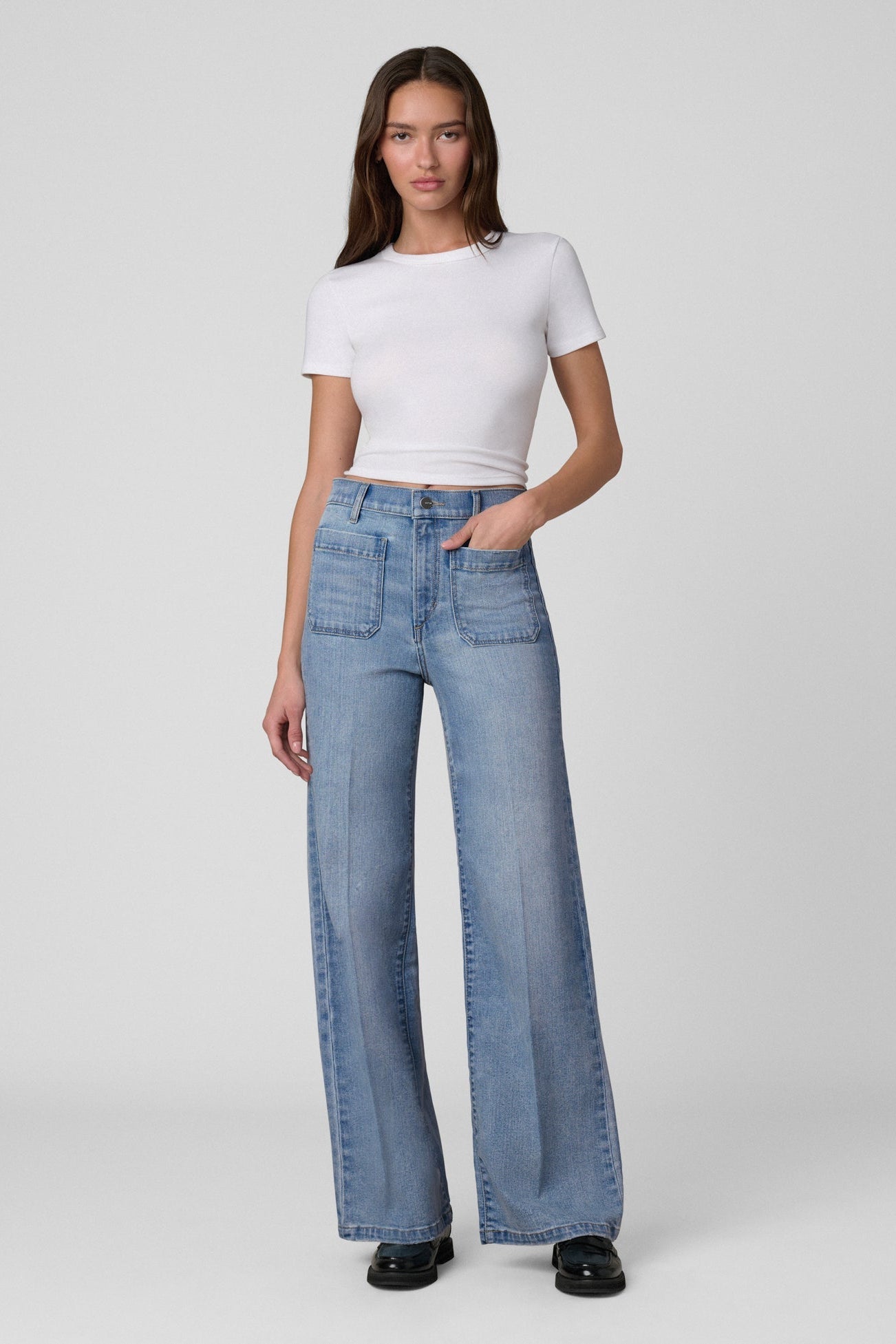 Woman wearing a white t-shirt and Joe's Mia Patch Pocket blue jeans in Amiable color on a white background