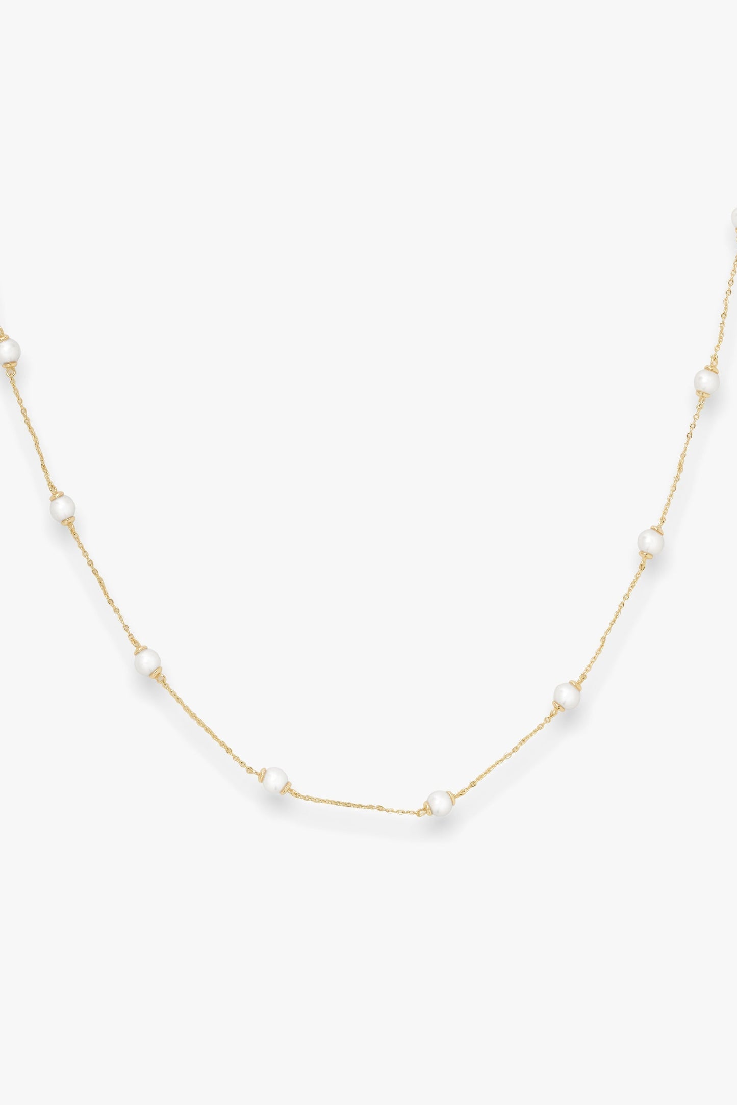 Gold infinity necklace with pearls on a white background