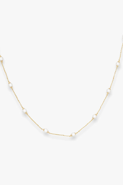 Gold infinity necklace with pearls on a white background