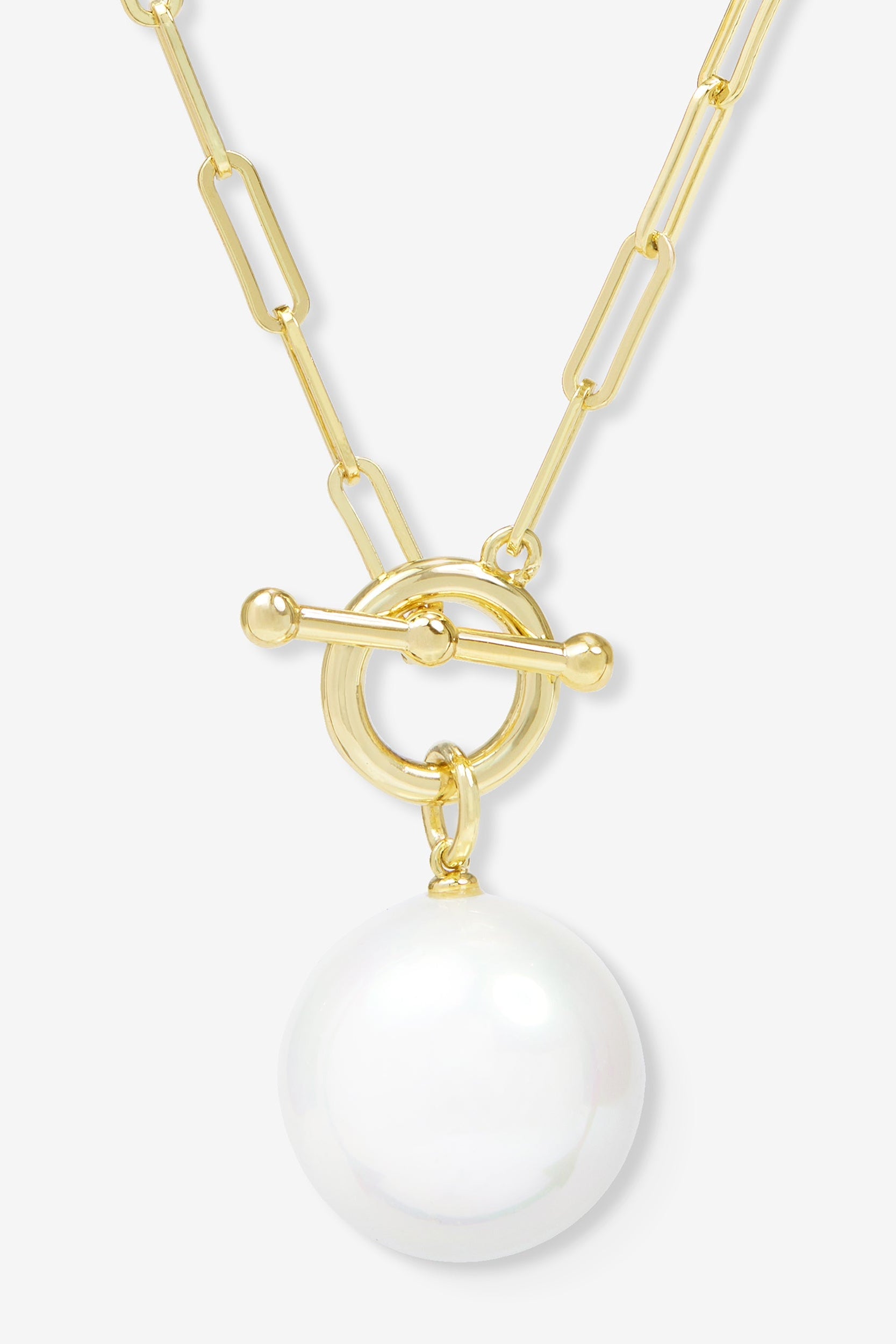 Gold necklace with a large white pearl pendant on a light gray background
