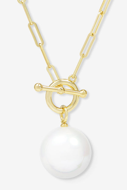 Gold necklace with a large white pearl pendant on a light gray background