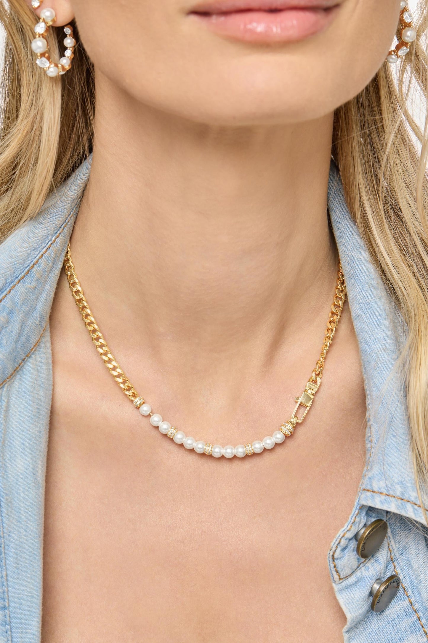 A close-up of a model wearing a delicate gold chain julian loves pearls necklace with a single row of small white pearls, styled with a light blue denim jacket.