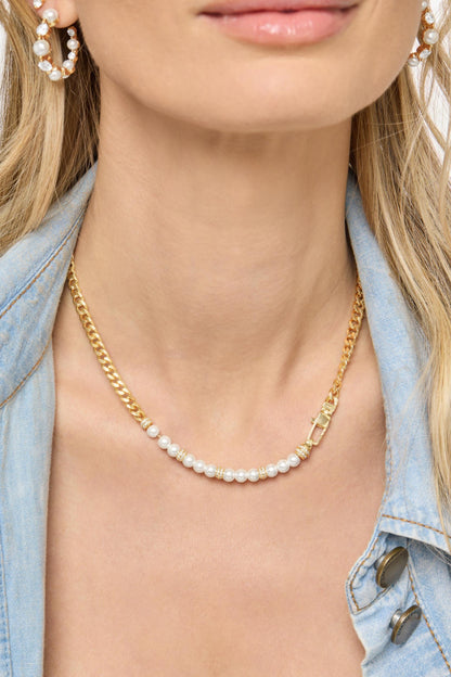 A close-up of a model wearing a delicate gold chain julian loves pearls necklace with a single row of small white pearls, styled with a light blue denim jacket.
