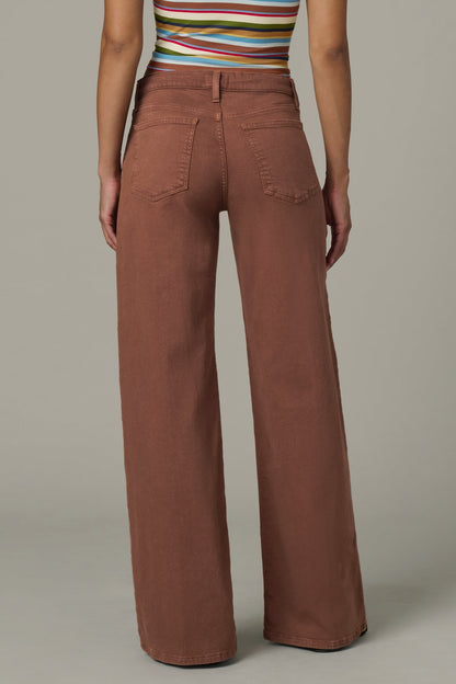 Back view of woman wearing a striped top and chocolate color Lou Lou wide-leg pants with a drawstring on a plain background