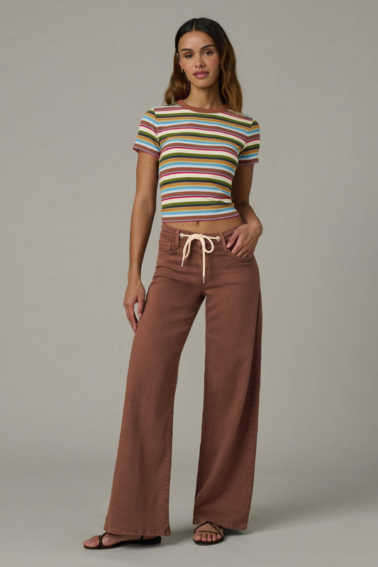 Woman wearing a striped crop top and chocolate color Lou Lou wide-leg pants  with a drawstring on a plain background