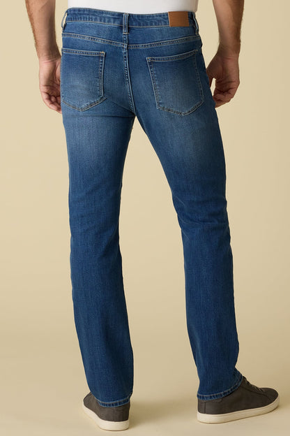 Back view of person wearing highland cooling nashville straight medium wash blue jeans on a beige background