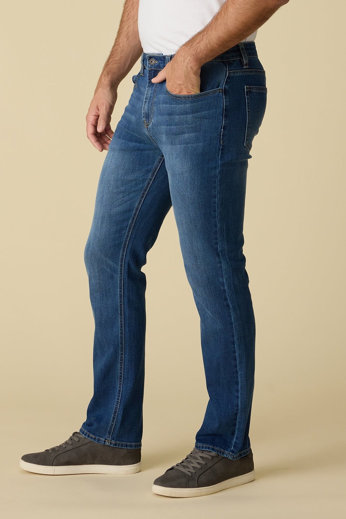 Side view of Person wearing highland cooling nashville straight medium wash blue jeans on a beige background