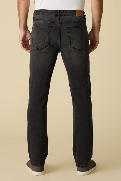 Back view of person wearing black Baytown cooling Nashville Straight jeans and a white shirt on a beige background