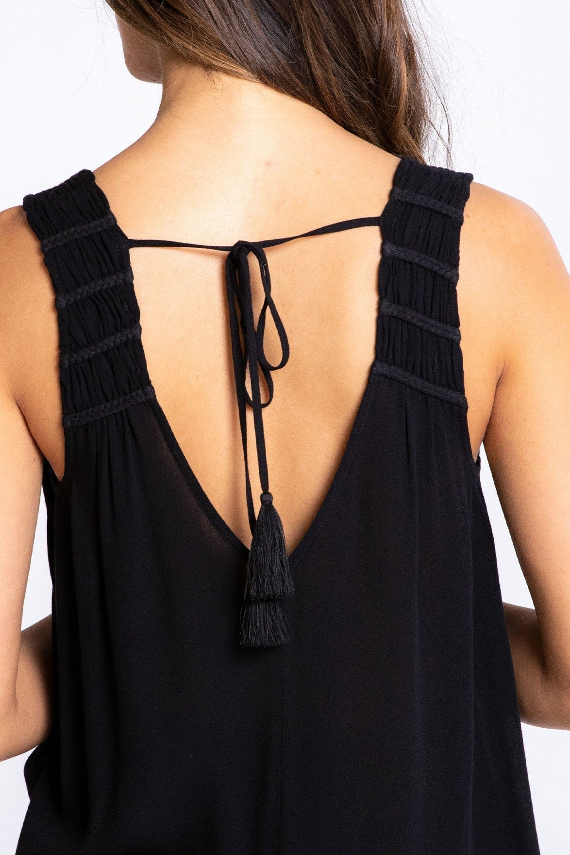 Black sleeveless top with open back and tassel details on a white background