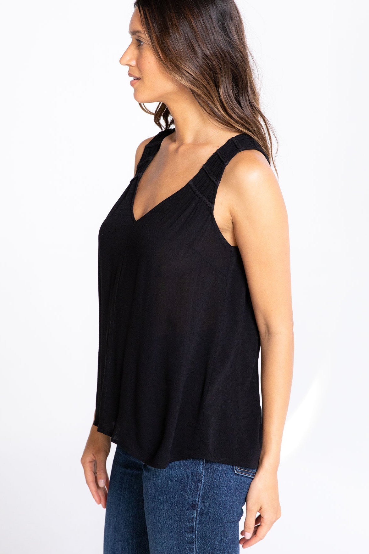 Woman wearing a black sleeveless top and blue jeans on a white background