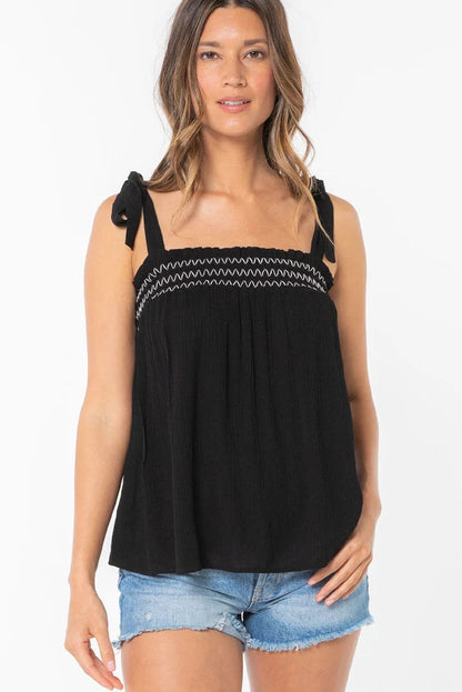 Black smocked tank top with zigzag trim and tie bow shoulder straps, front view