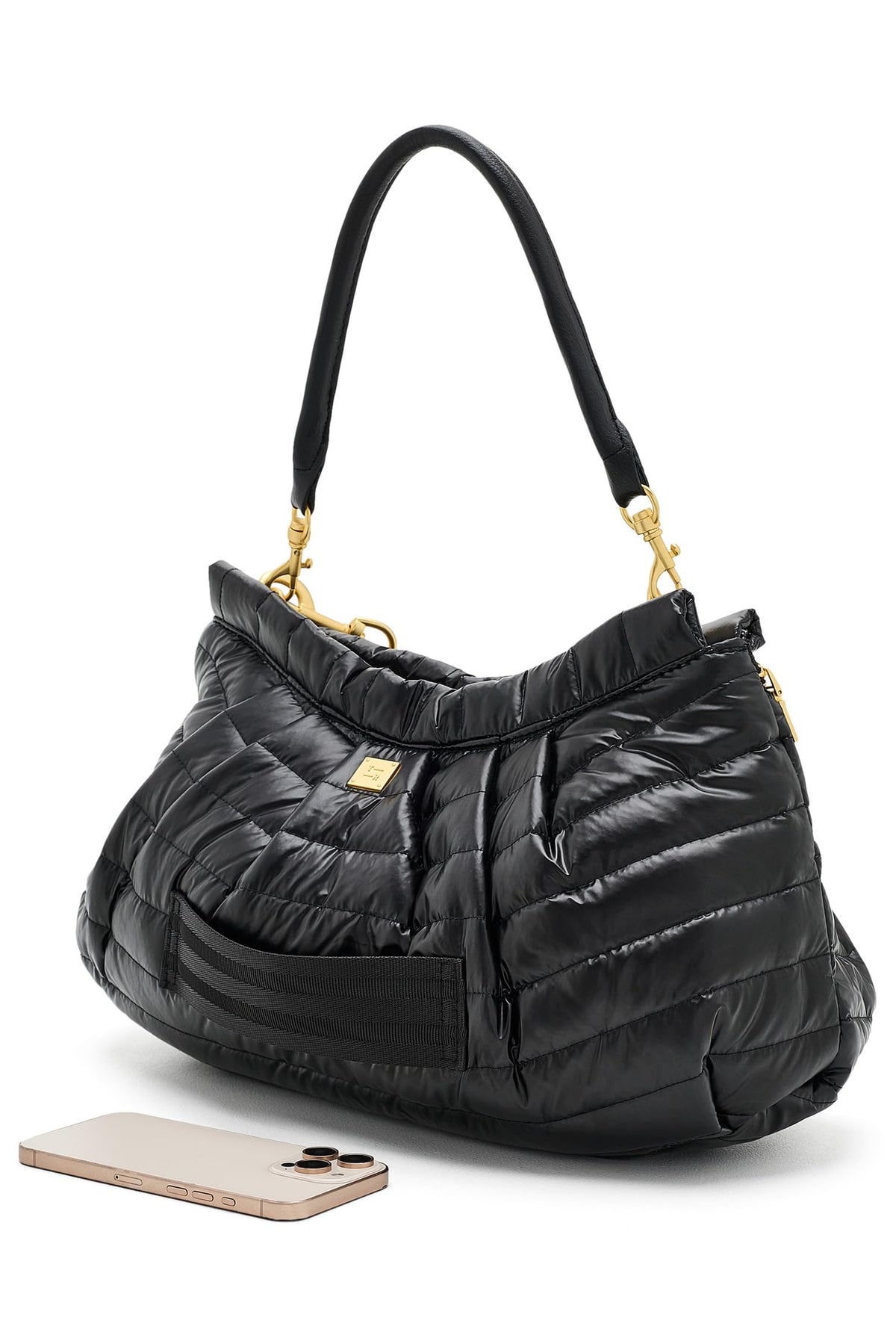 A black quilted hold me close clutch puffer handbag with gold-tone hardware and a black shoulder strap, shown on a white background with a smartphone placed in front for scale.