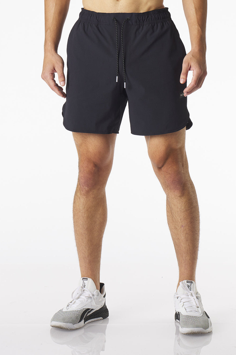 A man wearing black Luka HD athletic shorts and white and gray running shoes, shown from the waist down against a clean white studio background.