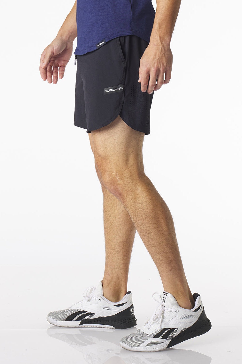 Side view of person wearing black Luka HD athletic shorts and white sneakers on a white background