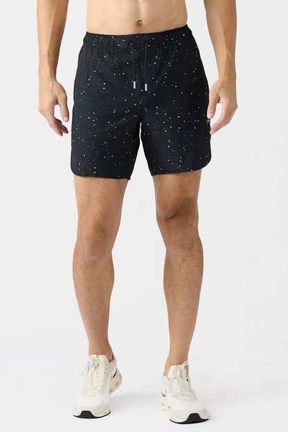 Person wearing black athletic shorts with white splatters on a white background
