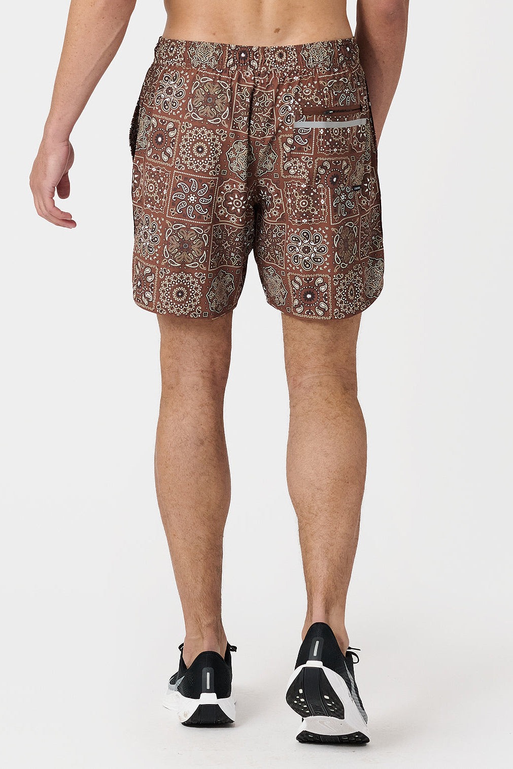 Person wearing paisley tile copper patterned shorts on a white background