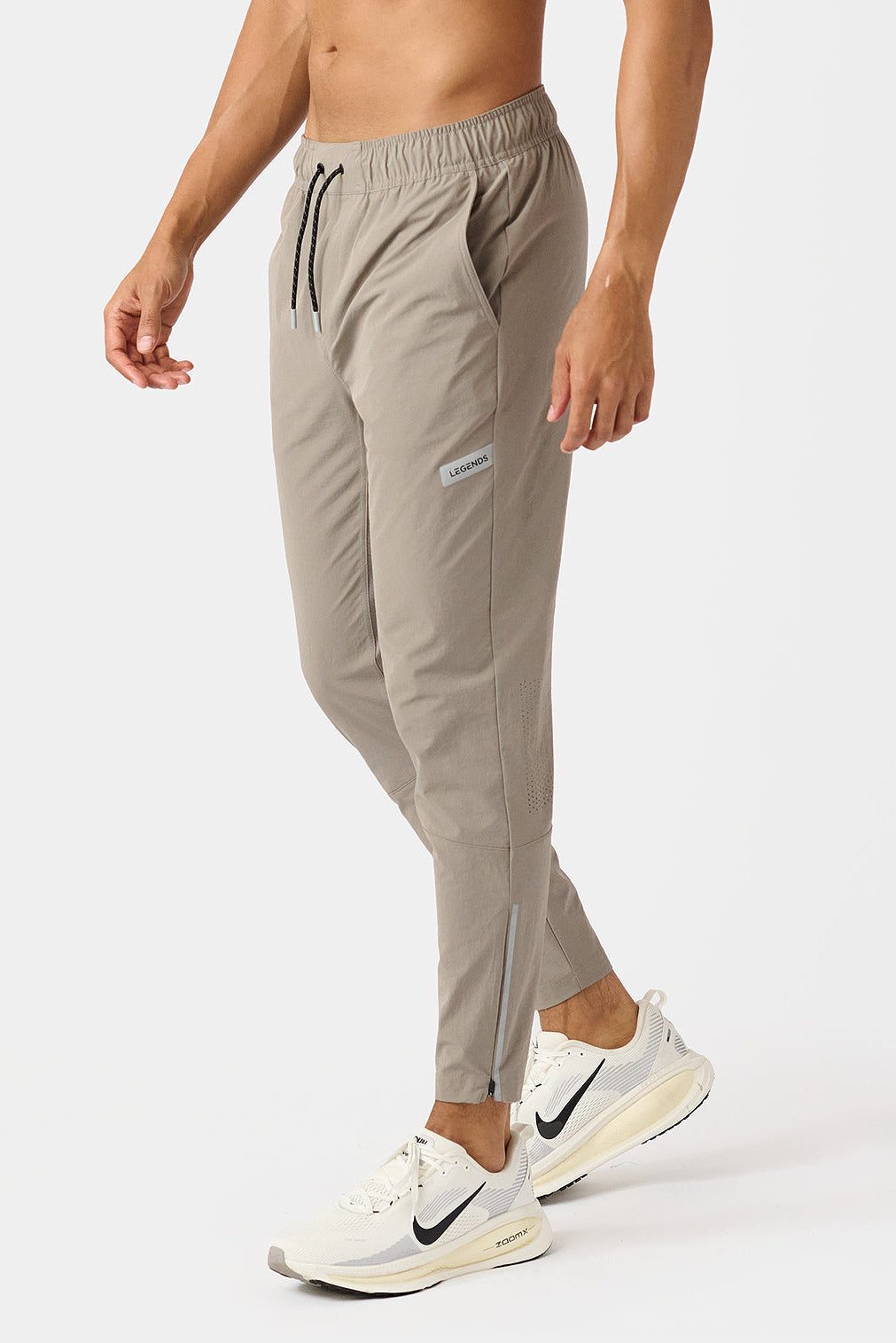 Person wearing taupe carson jogger pants with a brand logo on a white background