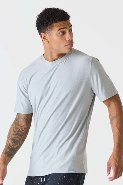 A man wearing a heather gray crew-neck t-shirt, shown from a three-quarters angle against a plain light gray studio background.