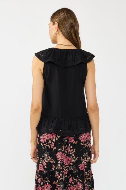 Back view of woman wearing a black sleeveless ruffle top with floral skirt on a white background