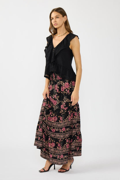 Woman wearing a black sleeveless ruffle top with floral pattern skirt on a white background