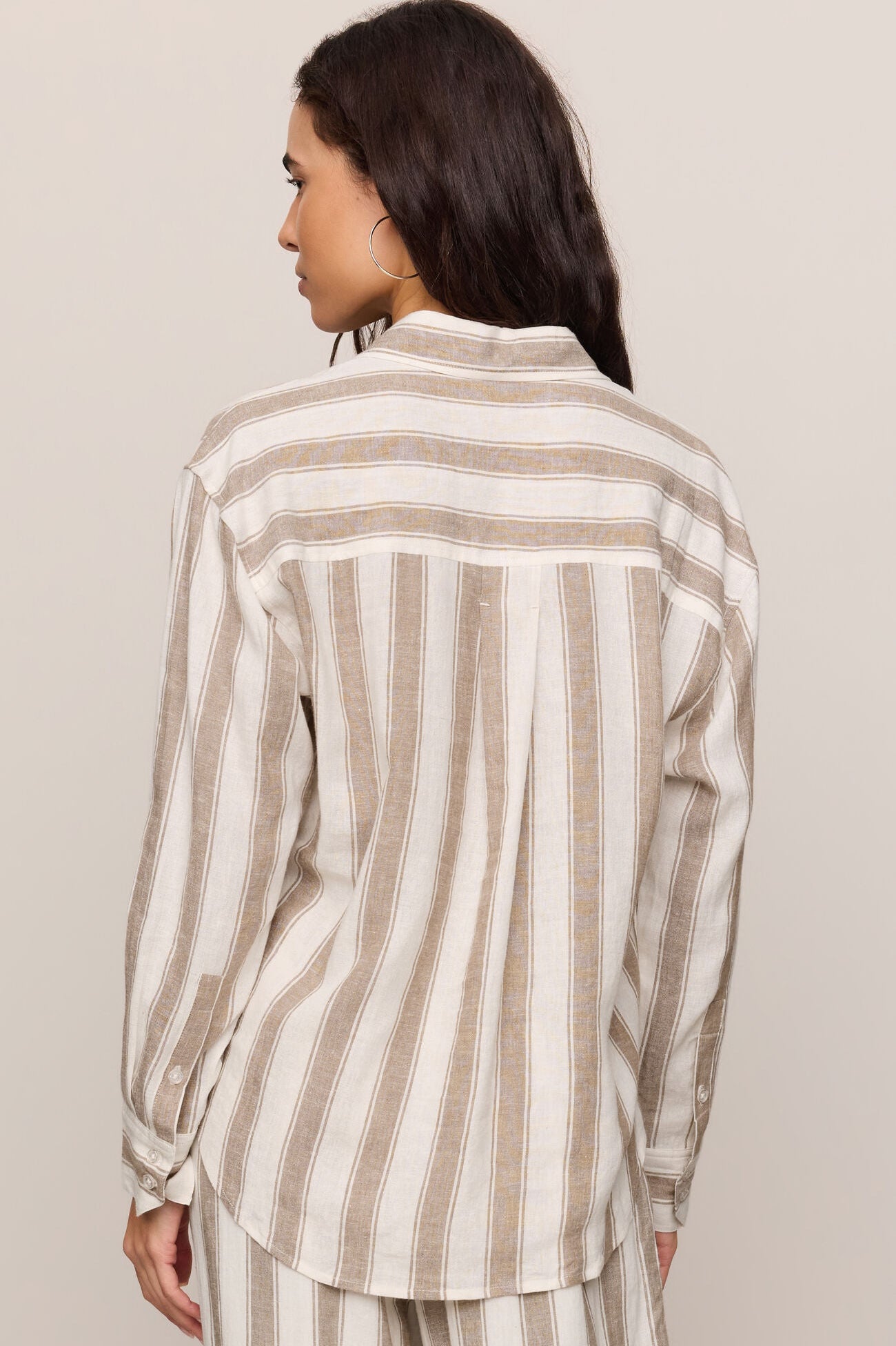 Back view of woman wearing a light toffee striped button up top and matching pants 