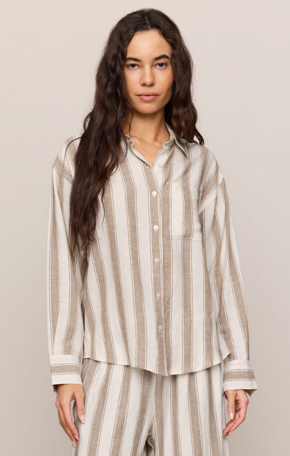 Woman wearing a light toffee striped button up top and matching pants 