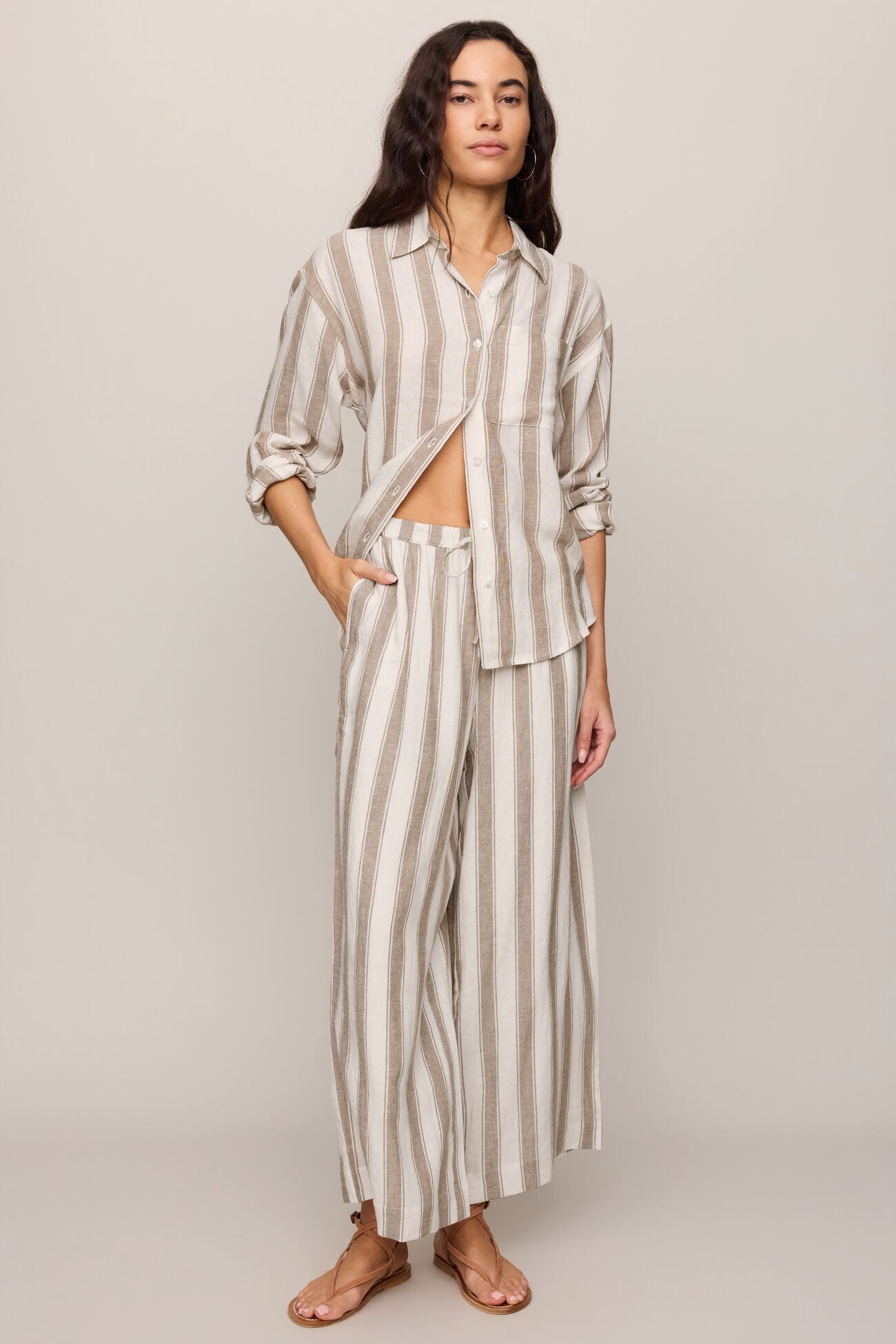 Woman wearing a light toffee striped button up top and matching pants 