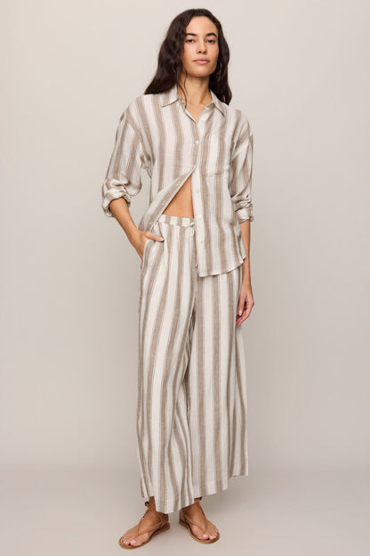 Woman wearing a light toffee striped button up top and matching pants 