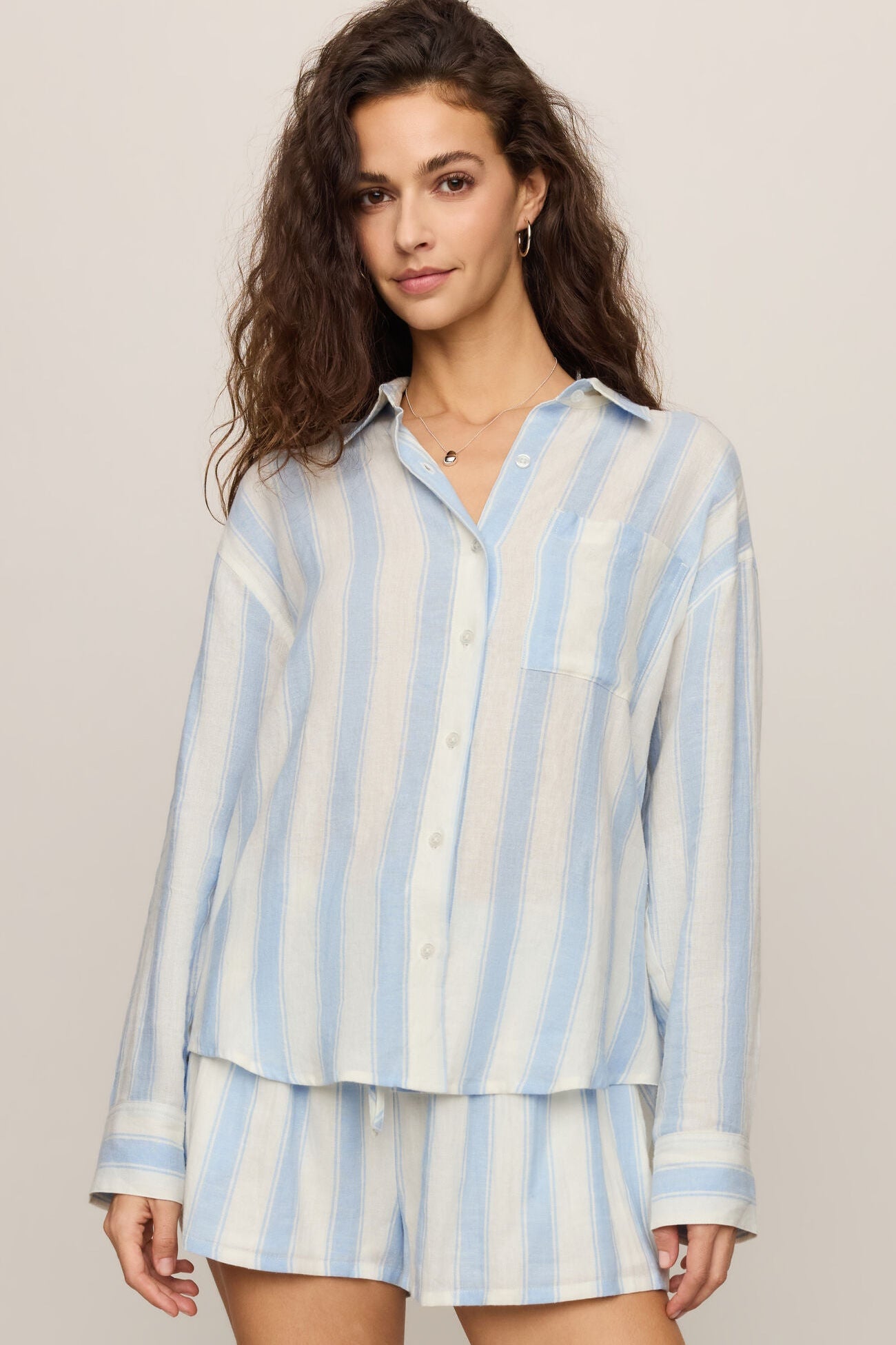 Woman wearing a skyline light blue and white striped shirt on a beige background