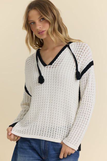Woman wearing an ivory crochet sweater with black accents on a beige background