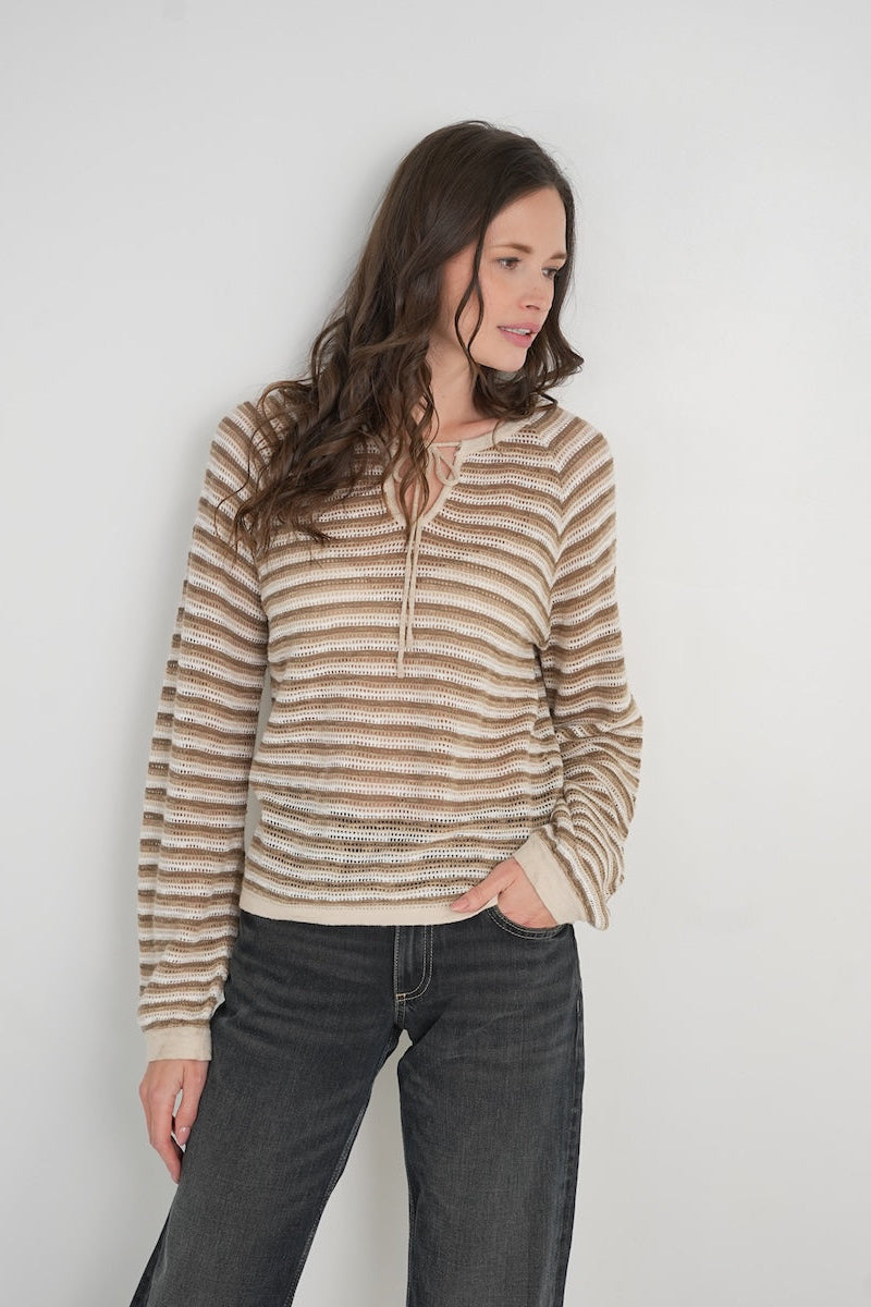 Woman wearing a tender striped sweater and dark jeans against a white background