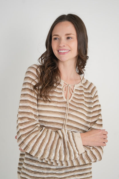 Woman wearing a tender striped sweater against a plain background