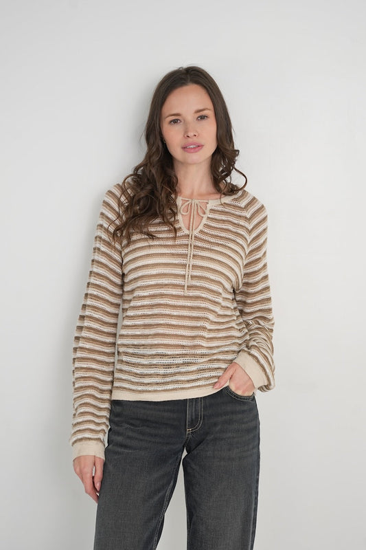 Woman wearing a tender striped sweater and jeans against a plain background