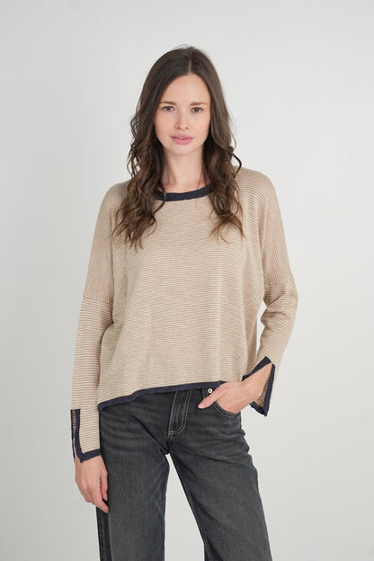Woman wearing a suede color sweater with black cuffs and trim on a white background
