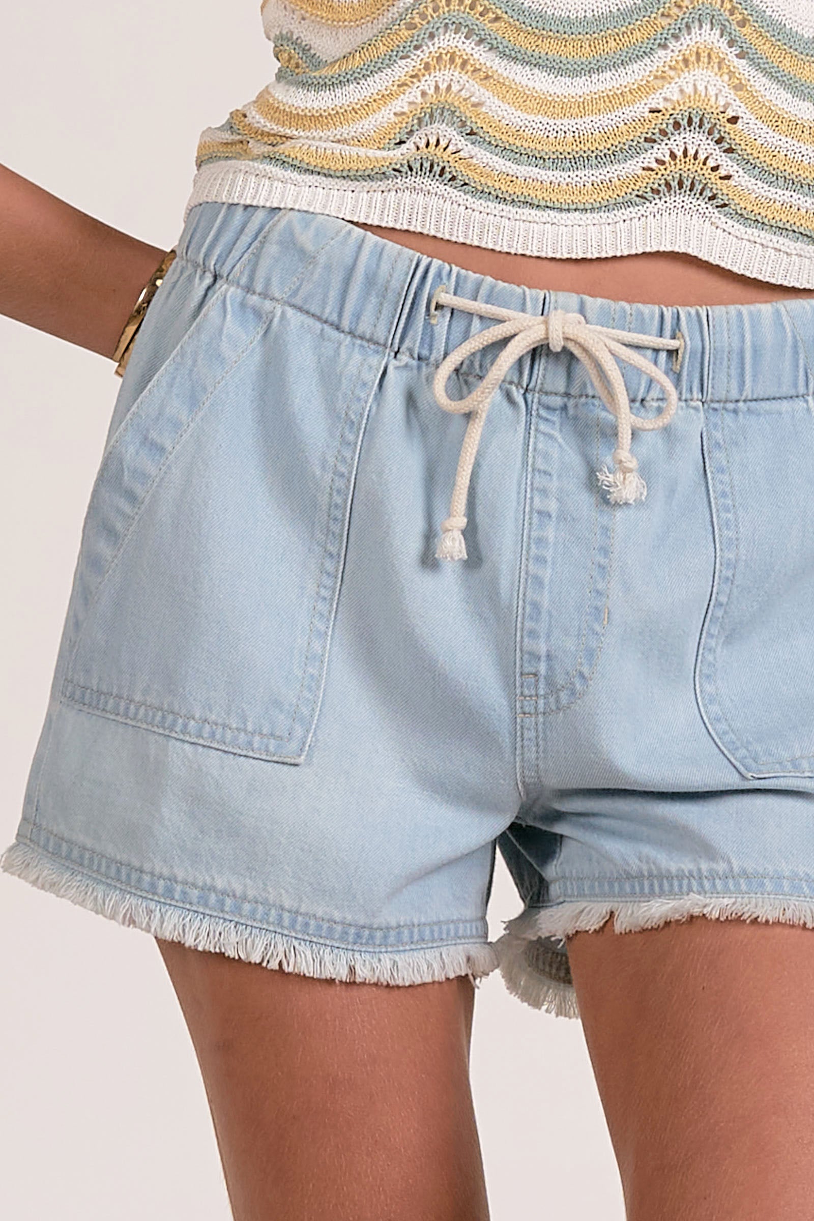 Close view of light blue denim shorts with a drawstring on a white background