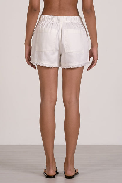 Back view of white fray shorts worn by a person on a plain background
