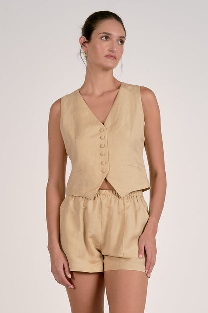 Front view of a woman wearing an oatmeal vest and shorts set on a plain background