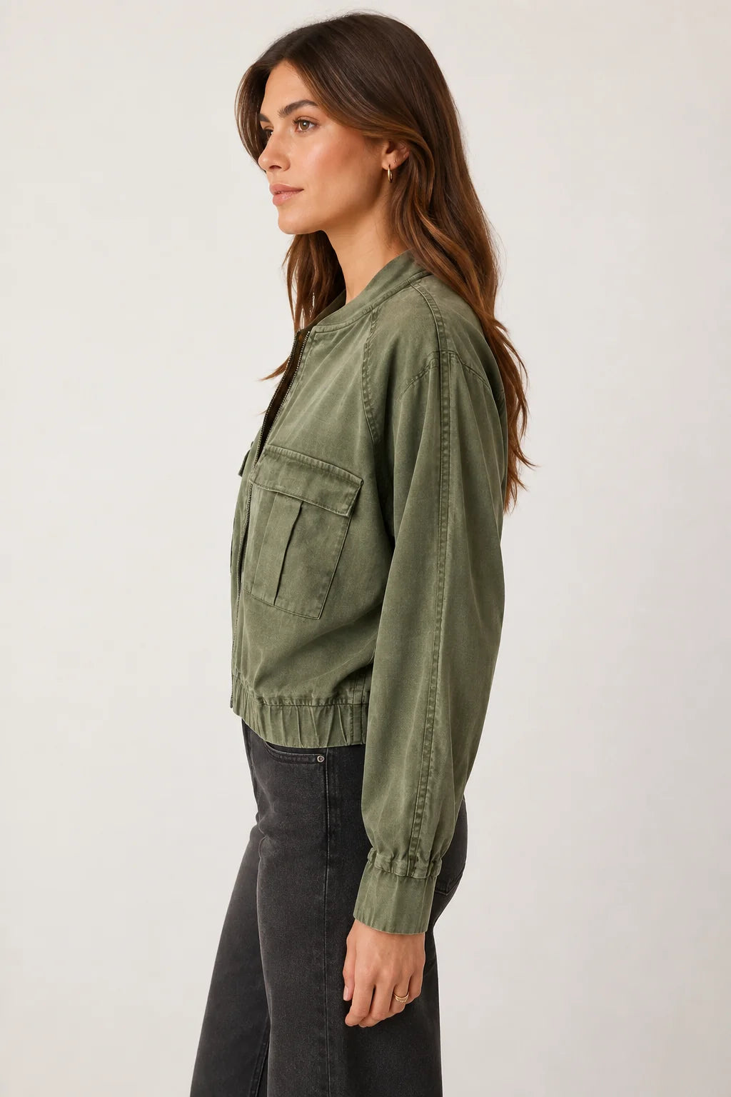 Woman wearing an avocado colored bomber jacket from the side 