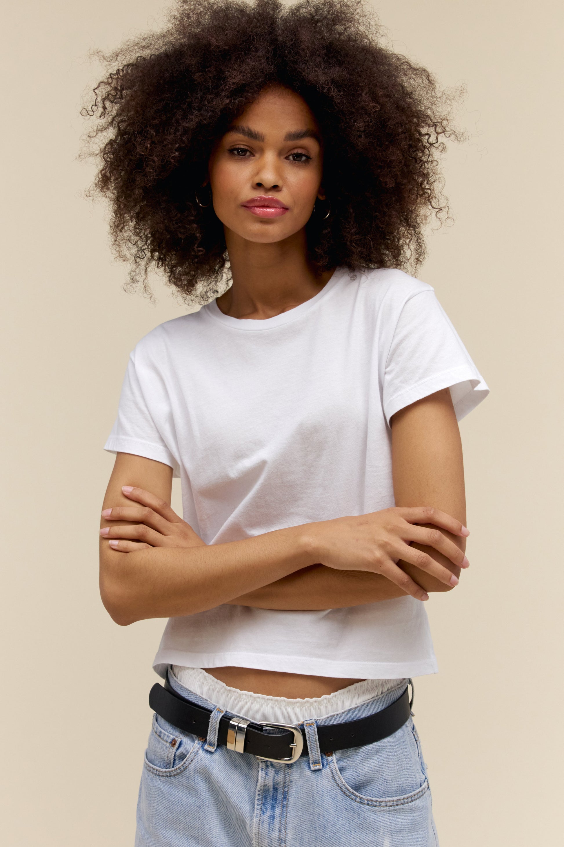 Woman wearing a bleach white t-shirt and blue jeans with a beige background
