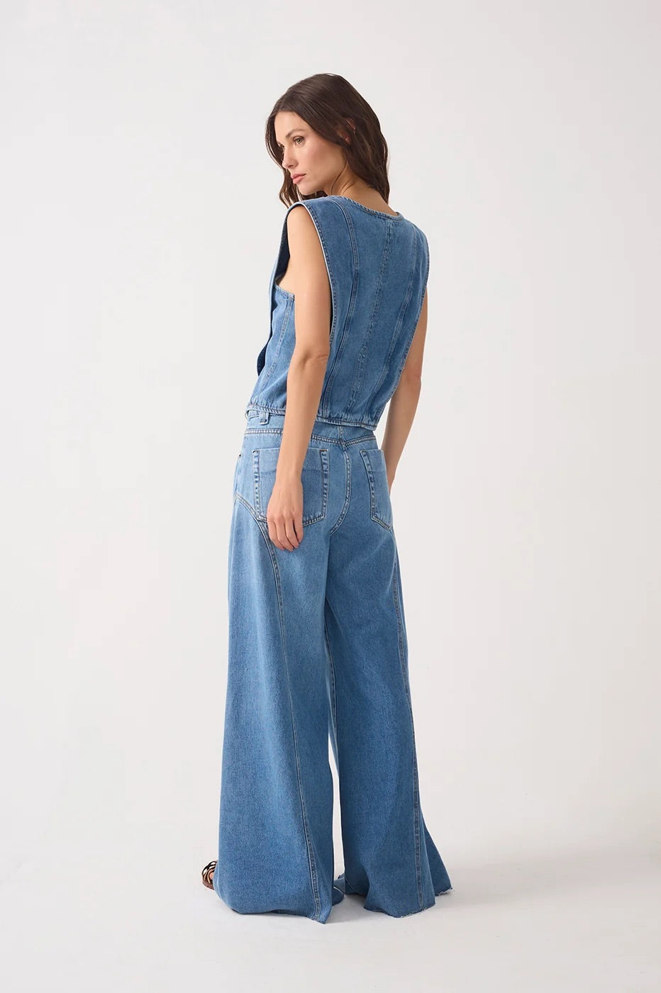 Back view of woman wearing a denim top and denim pockets belt loops flared pants 