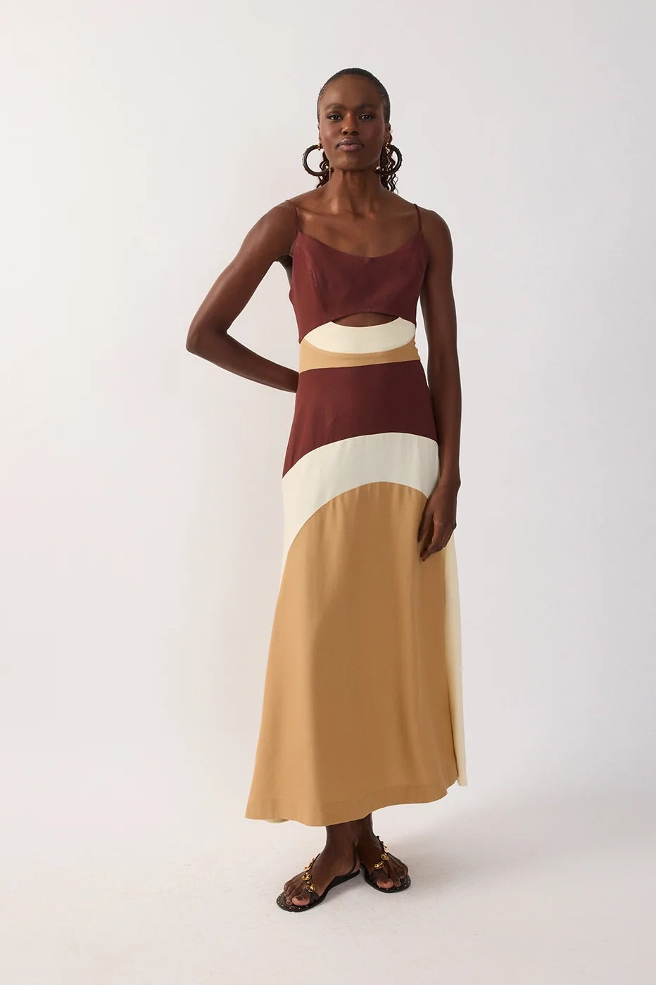 Woman wearing a multicolor-blocked dress with brown, white, and beige sections & a cutout on a white background
