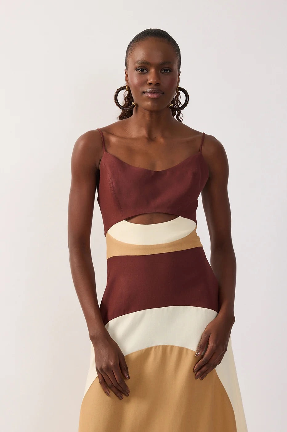 Woman wearing a multicolor-blocked dress with brown, white, and beige sections & a cutout on a white background