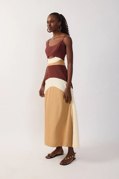 Side view of woman wearing a multicolor-blocked dress with brown, white, and beige sections & a cutout on a white background