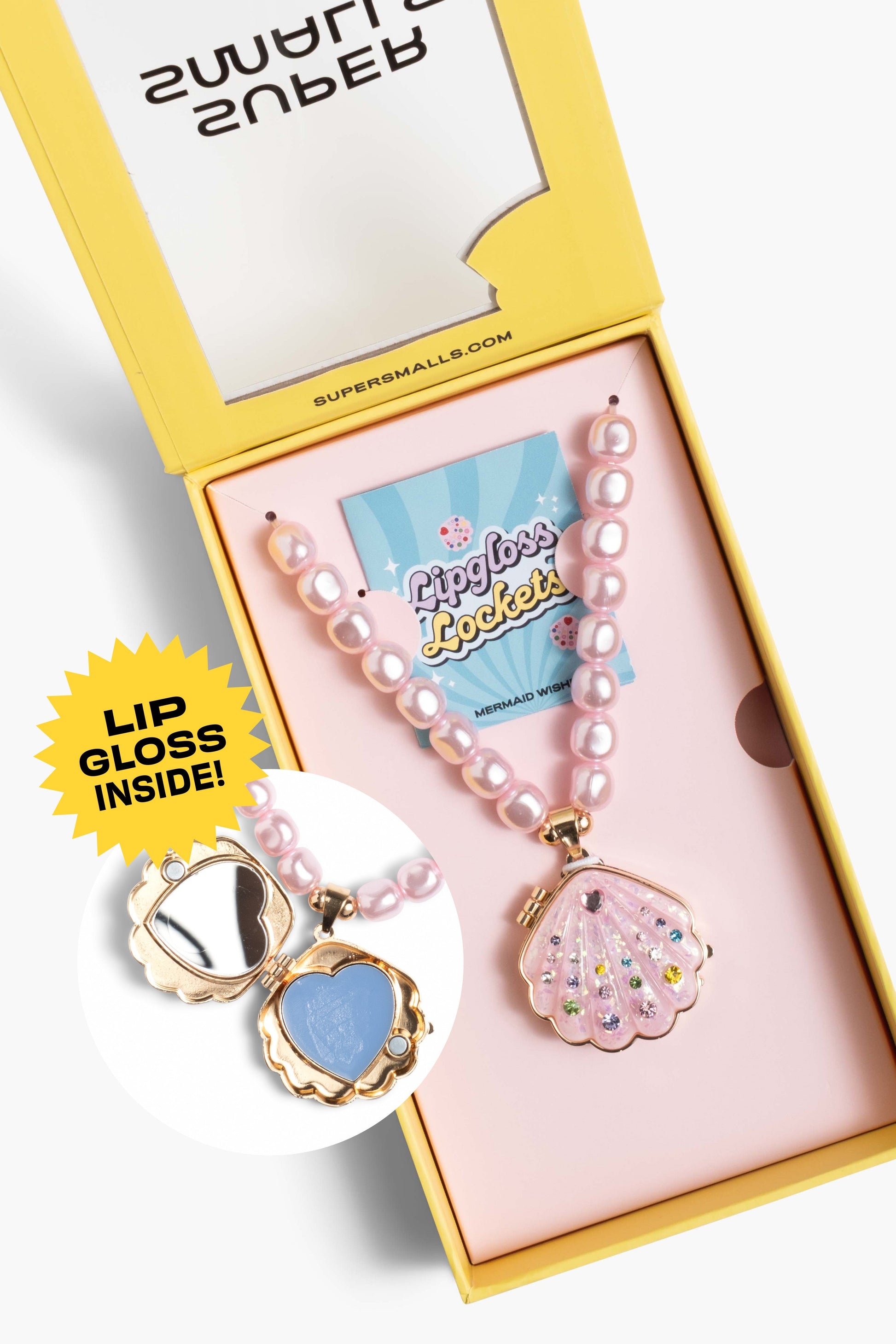 A pink pearl necklace with a sparkle pink clam-shell pendant containing rhinestones, presented in a yellow and pink gift box. A circular inset shows the inside of the clam pendant with a blue lip gloss layer inside and gold trim.