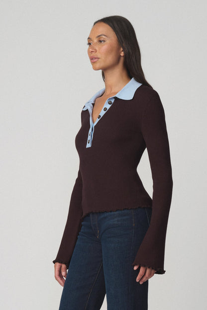 Side view of a woman wearing the riley polo sweater in espresso with a light blue collar and dark blue jeans 