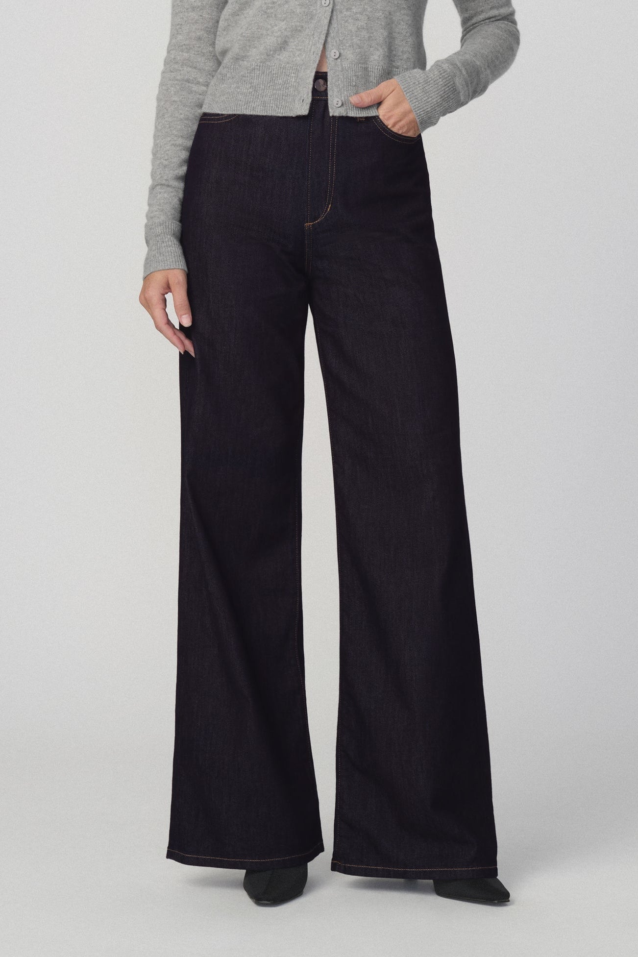 Front view of woman modeling a light gray cropped cardigan and the mia petite dark wide-leg jeans in 'absolutely' color against a plain light gray studio background.
