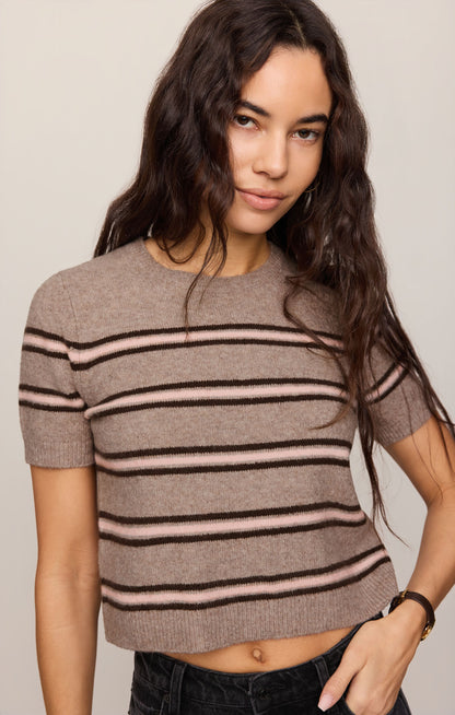 Close up of woman wearing a Gatewood striped sweater in Heather Ash color and black jeans against a plain background