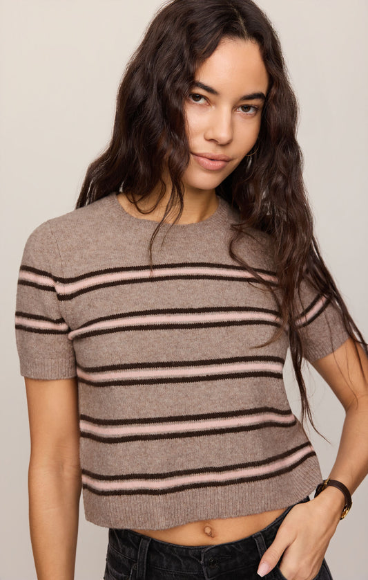 Close up of woman wearing a Gatewood striped sweater in Heather Ash color and black jeans against a plain background