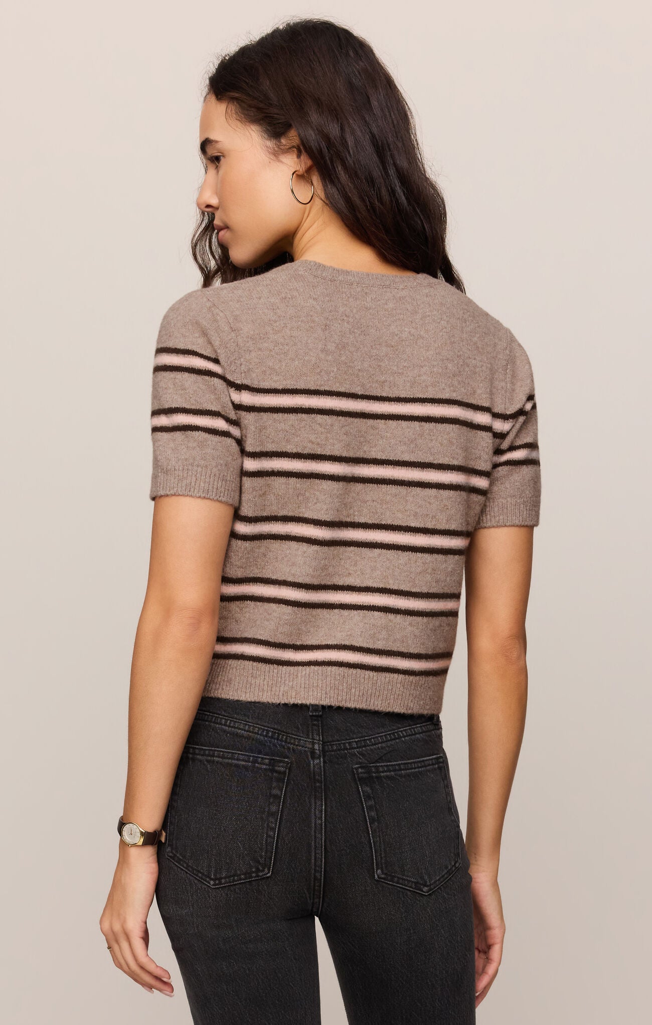 Back view of woman wearing a Gatewood striped sweater in Heather Ash color and black jeans against a plain background