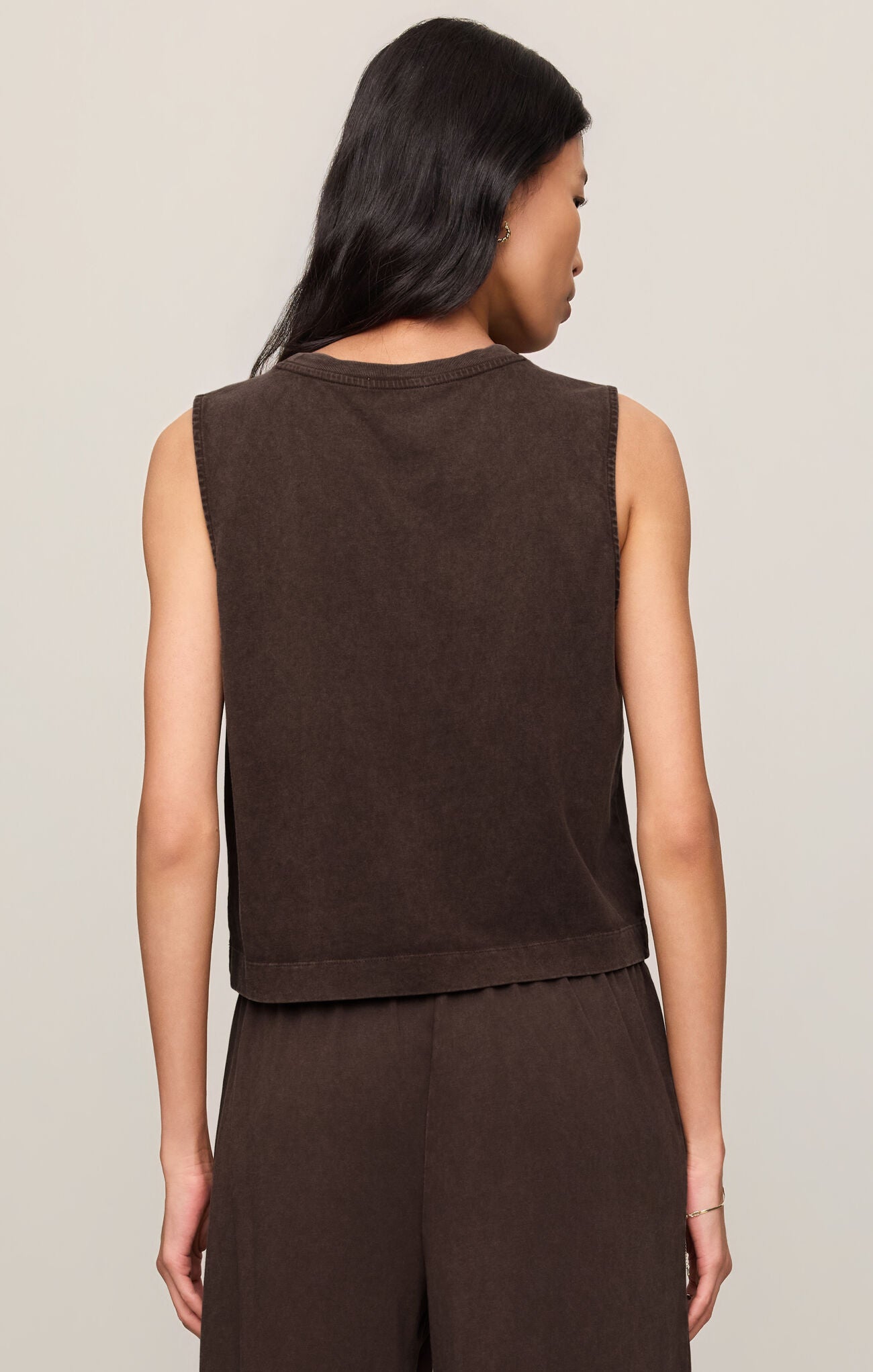 Back view of woman wearing a dark chocolate brown Sloane sleeveless tank top and pants against a neutral background